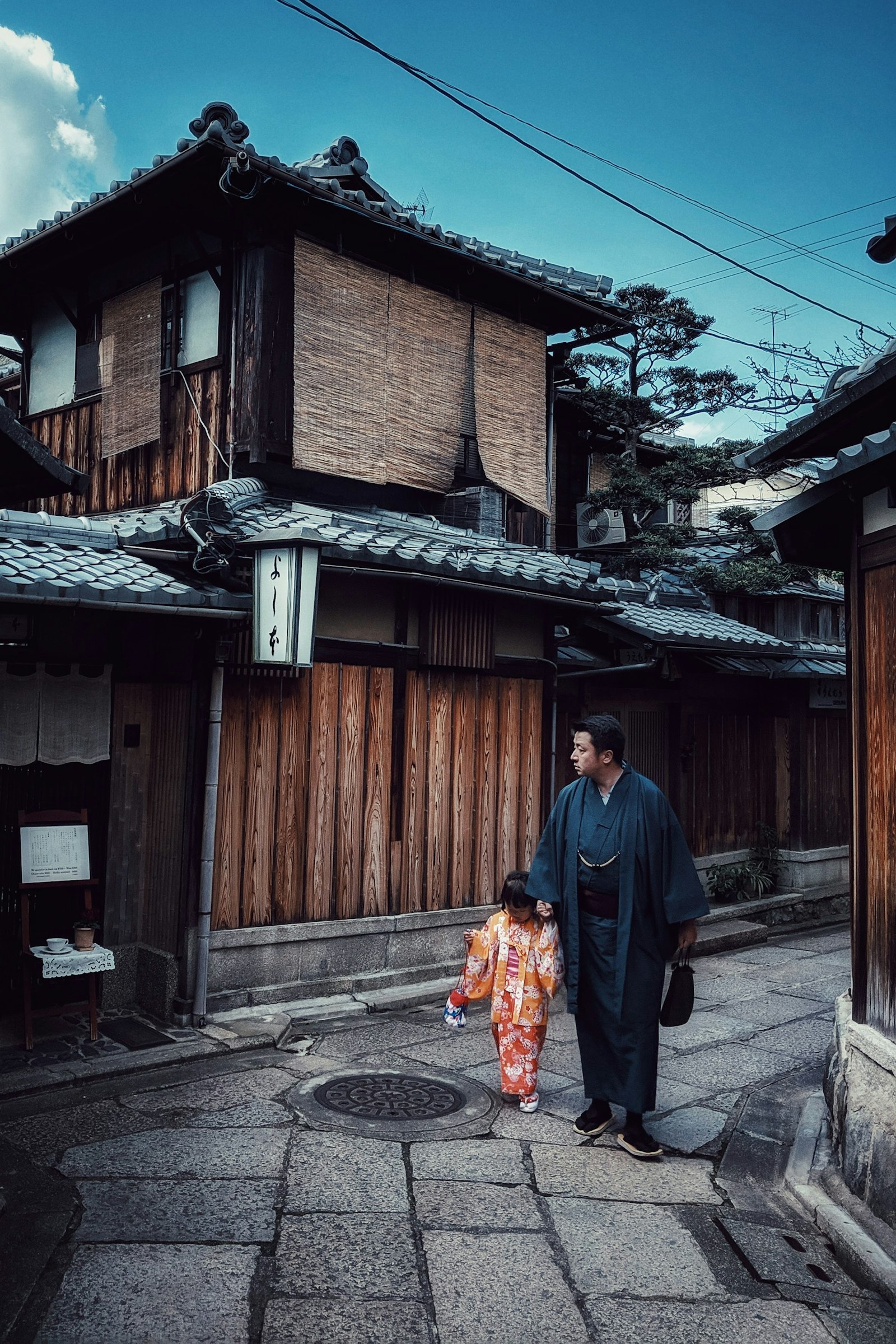京都の町家の路地を、手をつないで歩く親子